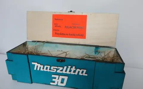 Otwarta, turkusowa skrzynka na 30 urodziny z napisem "Maszlitra 30". W środku sianko. Na wieczku etykieta "Najlepszy F(L)ACHOWIEC".