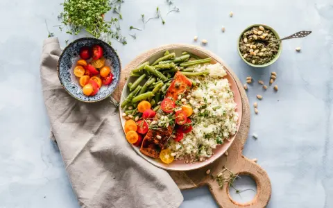Un délicieux repas parisien : saumon grillé, haricots verts, riz et tomates cerises, accompagné de pesto et de pousses fraîches.