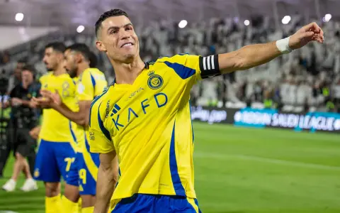 Uśmiechnięty Cristiano Ronaldo w żółtej koszulce Al Nassr, świętujący sukces. Jego zarobki w Arabii Saudyjskiej budzą podziw.