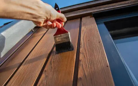 Application d'une couche protectrice sur des lattes de bois avec une peinture à l'huile sur bois technique.