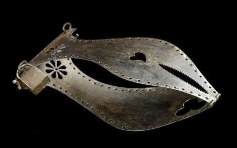 Metalowy pas cnoty, ozdobiony kwiatami i sercem, z ząbkowanym zamknięciem.