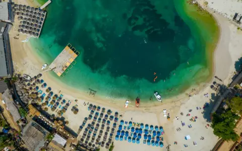Rajska plaża w Albanii, idealne miejsce na wakacje. Turkusowa woda, złoty piasek i mnóstwo leżaków pod parasolami.