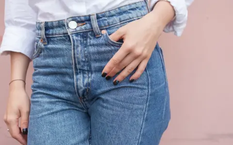 En hand vilar i fickan på ett par ljusblå jeans. Kanske är det en ny trend, jeans i frysen, för att få dem extra krispiga?