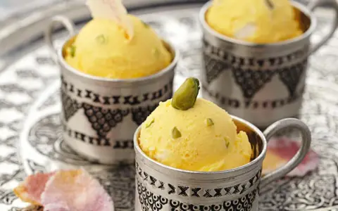 Gelbes Eis mit Pistazien in silbernen Bechern. Die süße Glucose-Verwendung sorgt für die cremige Konsistenz.