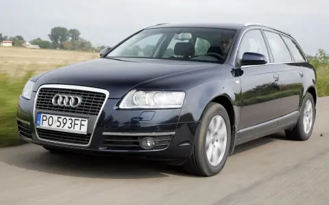 Ciemnogranatowe Audi A6 C6 3.2 FSI Avant w ruchu. Kierowca za kierownicą. Wady tego modelu mogą dotyczyć np. układu napędowego.