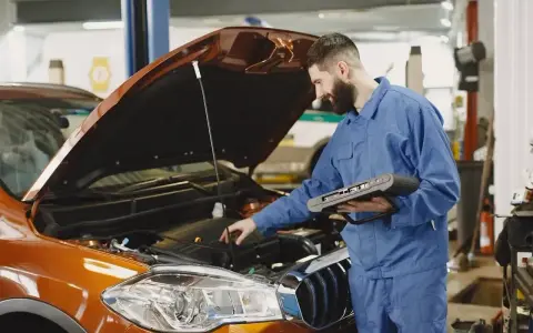 Mechanik z komputerem diagnostycznym sprawdza silnik. Zastanawiasz się, ile trwa wymiana oleju? To szybka usługa.