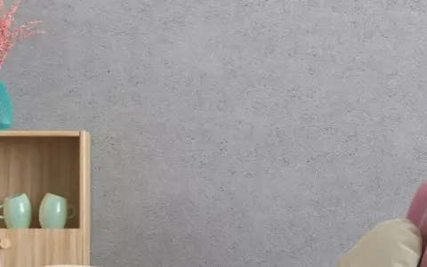 Un elegante papel pintado sobre gotele cubre la pared gris. Muebles de madera y tazas verdes decoran el espacio.