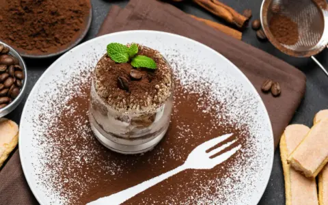 Pyszne tiramisu w pucharku, posypane kakao i kawą. Idealne desery co zamiast surowych jaj, z miętą i biszkoptami.