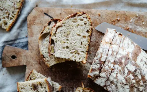 Frisches Brot mit Nüssen, perfekt **mit Dampf gebacken**, liegt auf einem Holzbrett.