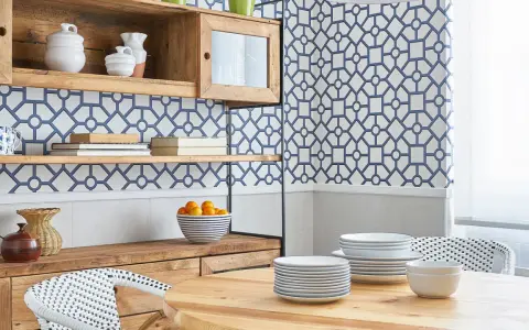 Cocinas con papel pintado azul y blanco, estanterías de madera, vajilla y una mesa de comedor.
