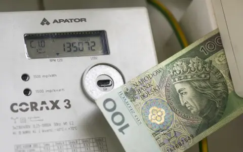 Licznik energii elektrycznej z banknotem 100 zł. Wysokie rachunki za prąd to problem, ale dodatek energetyczny może pomóc.
