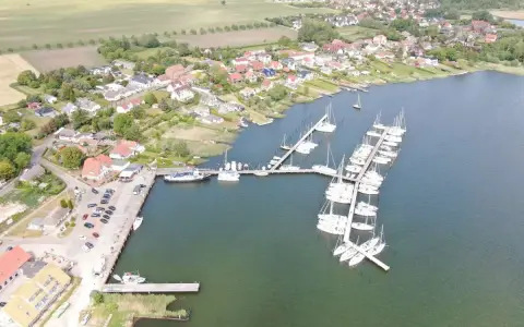 Breege Hafen: Viele Segelboote liegen im Hafen von Breege, umgeben von Häusern und grünen Feldern.