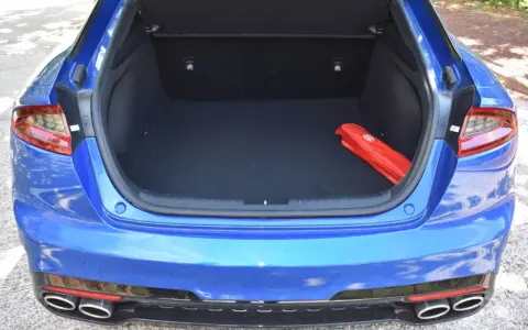 Maletero abierto de un Kia Stinger azul, con un botiquín rojo en el interior.
