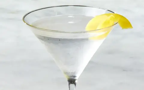 Chłodny martini z ginem, ozdobiony skórką cytryny, czeka na degustację.