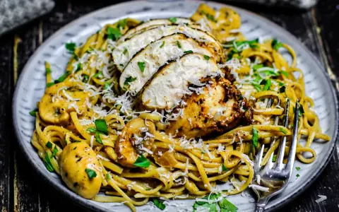 Cremiges Chicken Alfredo mit Pilzen, garniert mit Parmesan und Petersilie. Ein köstliches Gericht, das Lust auf mehr macht.