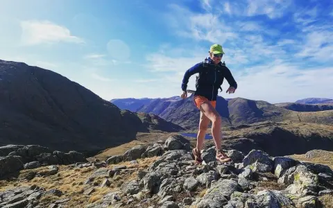 Atleta corre su sentiero roccioso in montagna. Il fast hiking significato è correre in montagna con attrezzatura leggera.