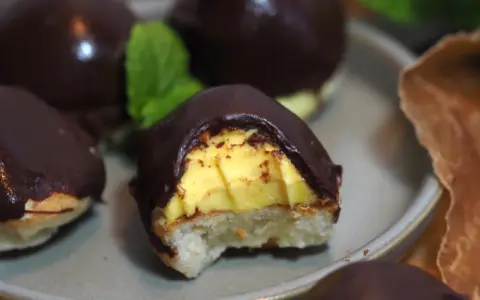 Chokladöverdragna biskvier med gul kräm och en bit av en mintkvist. Perfekt för att frysa in och njuta av senare.