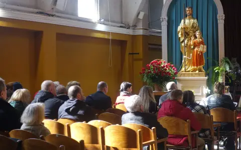 Ludzie w kościele, przed ołtarzem z figurą św. Józefa i Dzieciątka Jezus. W tle bukiet czerwonych róż. Sanktuarium Matki Bożej Częstochowskiej.