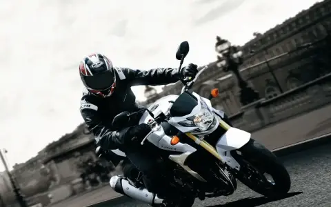 Motocyklista na białym Suzuki GSR 750 pokonuje zakręt. Nawet z potencjalnymi wadami, jazda nim to czysta przyjemność.