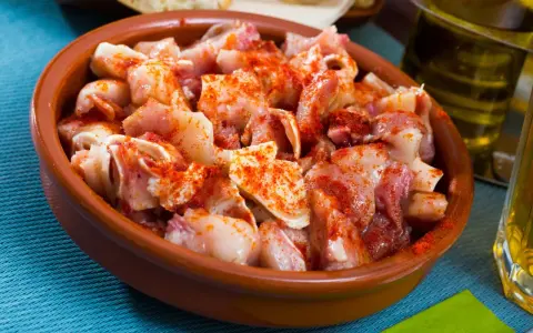 Oreja a la gallega, trozos de oreja de cerdo con pimentón en una cazuela de barro, listos para disfrutar.