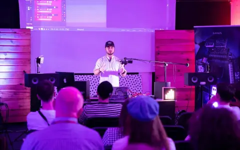 Prezentacja muzyczna z efektami, jak spring reverb. Mężczyzna mówi do mikrofonu, na ekranie widać program do produkcji muzyki.