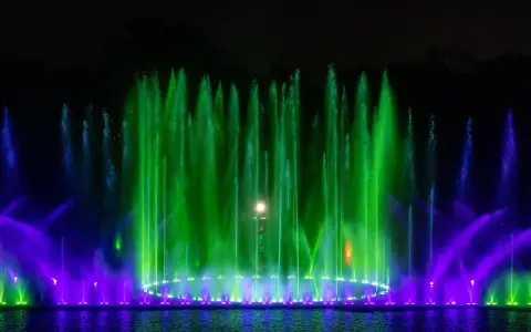 Spektakularna fontanna multimedialna we Wrocławiu nocą, tańczące strumienie wody w zielonych i fioletowych barwach tworzą magiczny pokaz.