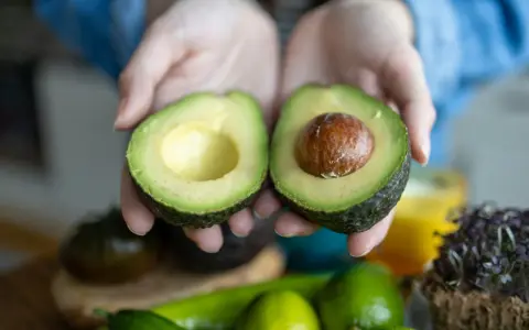 Hände halten eine aufgeschnittene Avocado. Tipps für avocado haltbar machen.
