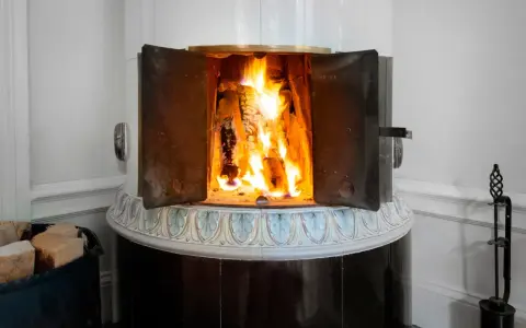 En öppen kamin med flammande ved. Det kan vara farligt att elda i kamin om man inte är försiktig.