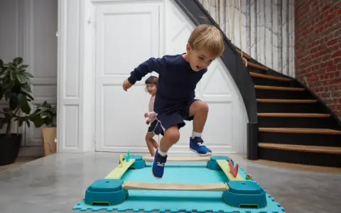 Bambini di 4 anni si divertono con la psicomotricità, saltando su un percorso a ostacoli colorato.