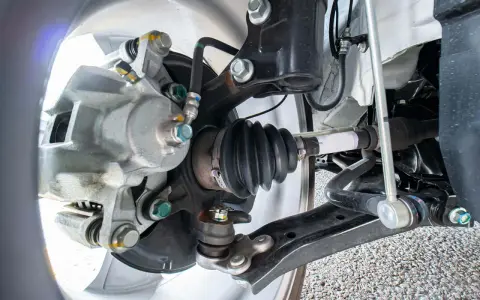 Parti di un'auto: pinza freno, giunto sferico e semiasse con soffietto integro, pronto per la sostituzione in caso di rottura semiasse.