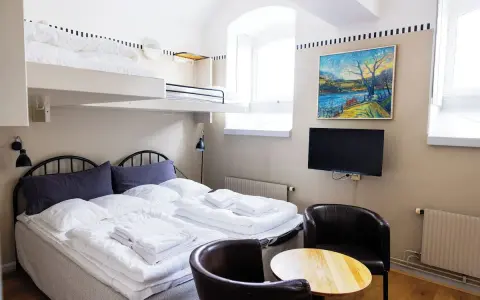 Ett mysigt rum på Langholmen Hotel med våningssängar, dubbelsäng, konst och TV.