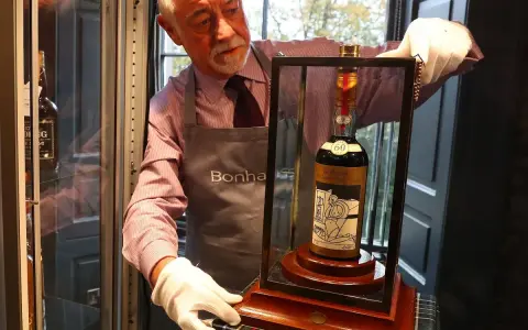 Mann mit weißen Handschuhen präsentiert eine Flasche des teuersten Weins der Welt, eine seltene Macallan 60 Year Old.