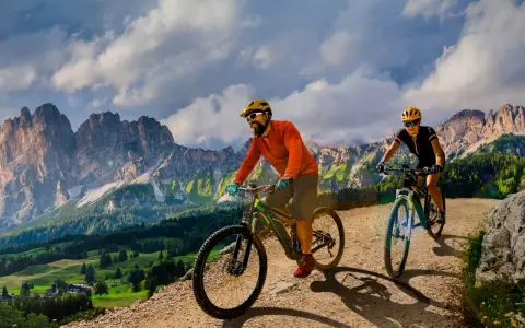 Due ciclisti si godono uno sport di montagna su sentieri sterrati con maestose vette sullo sfondo.