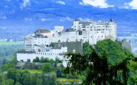 Majestatyczna twierdza Hohensalzburg, jedna z głównych salzburg atrakcje, góruje nad zielonymi wzgórzami.