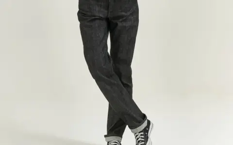 Uomo con jeans scuri e sneakers, che incarnano il comfort fit significato di libertà di movimento e stile casual.