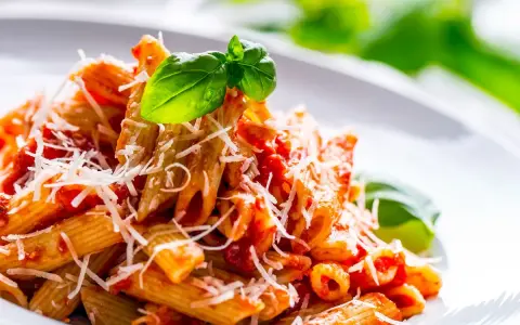 Penne al pomodoro con basilico fresco e parmigiano grattugiato, un classico tra i sughi per pasta.