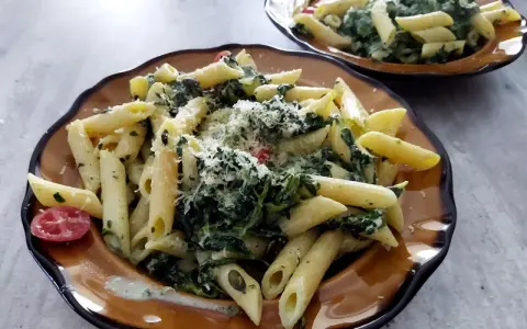 Penne z fetą i szpinakiem, posypane parmezanem. Idealny przepis na makaron ze szpinakiem i fetą.
