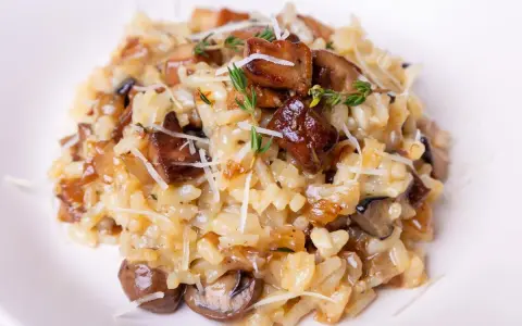 Aksamitne risotto z grzybami, posypane parmezanem i gałązkami tymianku, kusi apetycznym wyglądem.