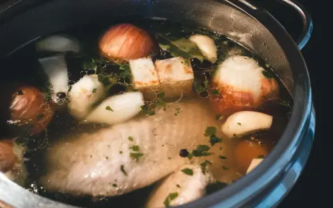 Szybkowar z bulionem: kawałki mięsa, cebula, czosnek, ziele angielskie i natka pietruszki tworzą aromatyczny rosół.