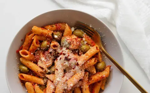 Penne z sosem pomidorowym, oliwkami i startą mozzarellą, posypane płatkami chili. Idealny makaron z mozzarellą na szybki obiad.