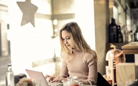 Kvinna skriver tack mail efter intervju på sin laptop vid ett bord med en tekanna.