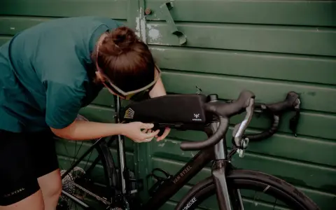 Osoba montuje torbę podsiodłową do roweru. Przygotowania do składania roweru przed wyprawą.