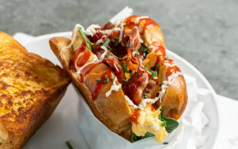 Herzhaftes **egg drop sandwich** mit Speck, Käse und Ketchup, daneben ein gegrilltes Käsebrot.