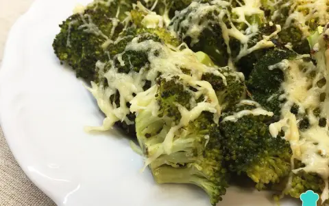 Brocoli al horno gratinado con queso, servido en un plato blanco.