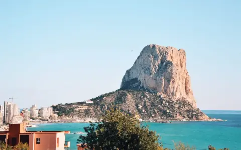 Widok na majestatyczną skałę Peñón de Ifach, symbol Costa Blanca atrakcje. Turkusowe morze i zabudowania miasta tworzą malowniczy krajobraz.