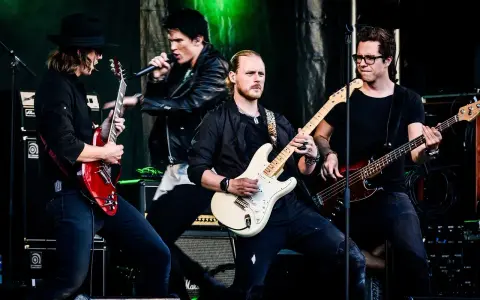 Zespół gra na scenie, wokalista śpiewa, gitarzyści i basista tworzą muzykę. Może to piosenka "Kocham Cię".