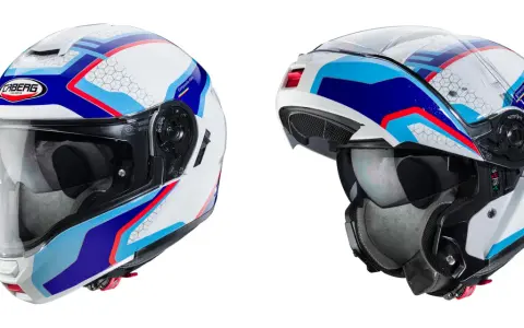 Due caschi integrali Caberg bianchi con grafiche blu, rosse e azzurre. Il casco integrale significa massima protezione.