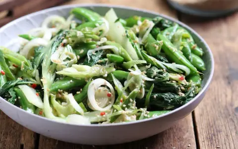 Sałatka z pak choi, groszku cukrowego i cebuli dymki, posypana sezamem. Idealna do dań kuchni azjatyckiej, świetne przepisy na kapustę pak choi.