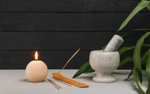 Vela encendida, mortero de mármol y varios tipos de sahumerios con humo ascendente, creando un ambiente sereno.