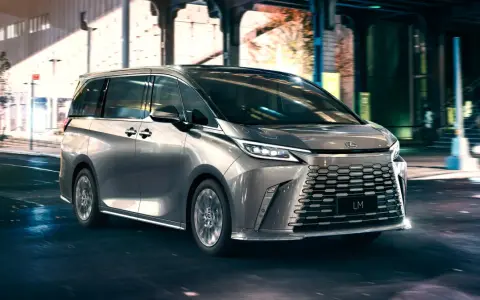 Srebrny van Lexus LM 350h na nocnej ulicy z rozmytym tłem.